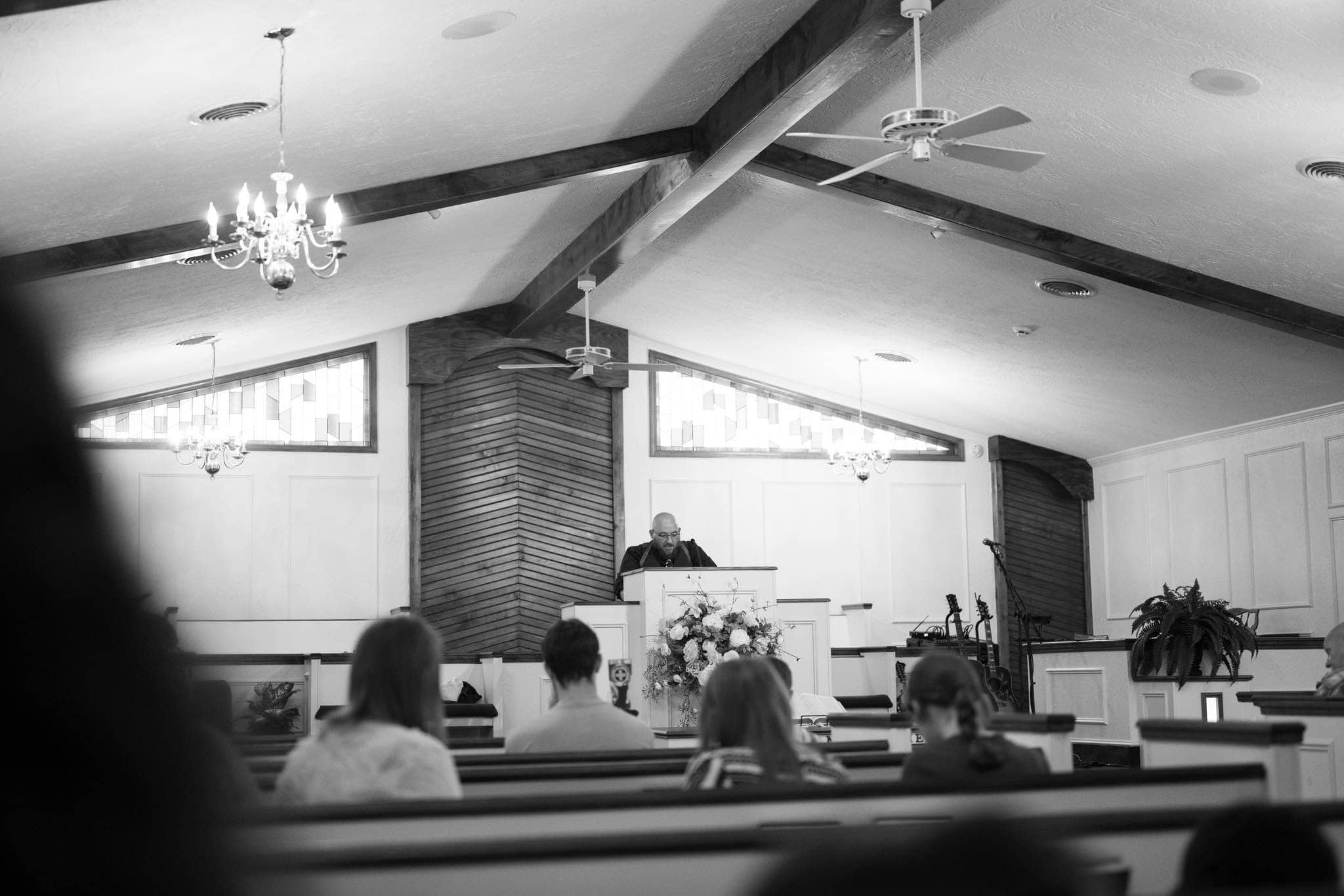 A black and white photograph of Kiefer preaching from a pulpit to a small congregation.