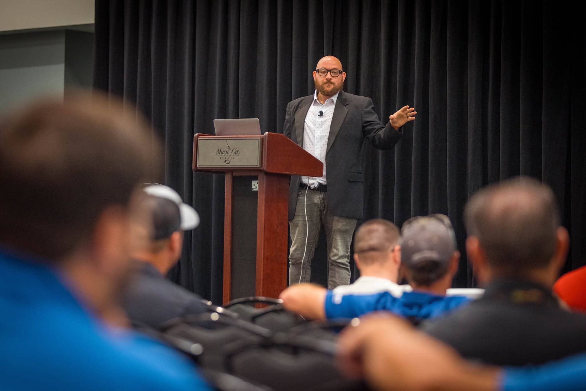 Kiefer speaking to a seated audience from a lectern at a conference.